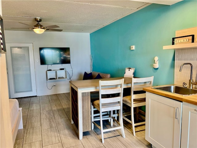 dining room featuring ceiling fan, sink, and a textured ceiling