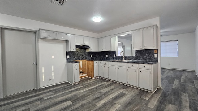 kitchen featuring dark countertops, visible vents, white cabinets, and a sink