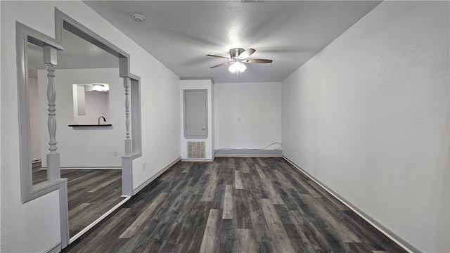 spare room featuring dark wood-style floors, ceiling fan, visible vents, and baseboards