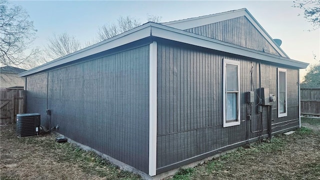 view of side of home featuring cooling unit and fence