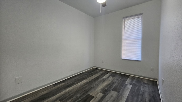 empty room with baseboards, dark wood finished floors, a ceiling fan, and a textured wall