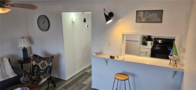 kitchen with dark hardwood / wood-style floors, a breakfast bar, black electric range, and white fridge