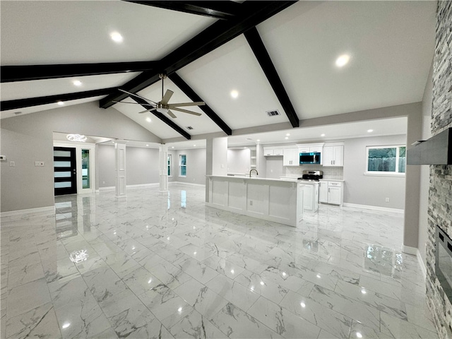 unfurnished living room featuring vaulted ceiling with beams, ceiling fan, ornate columns, and sink