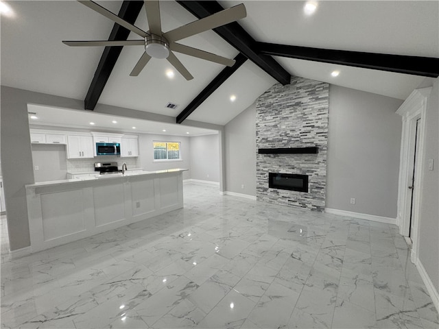 unfurnished living room with high vaulted ceiling, a fireplace, beamed ceiling, sink, and ceiling fan