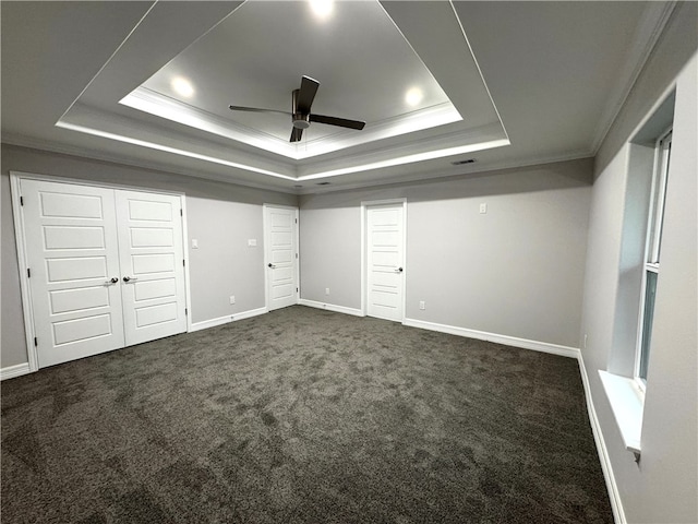 unfurnished bedroom featuring dark carpet, a raised ceiling, ceiling fan, and ornamental molding