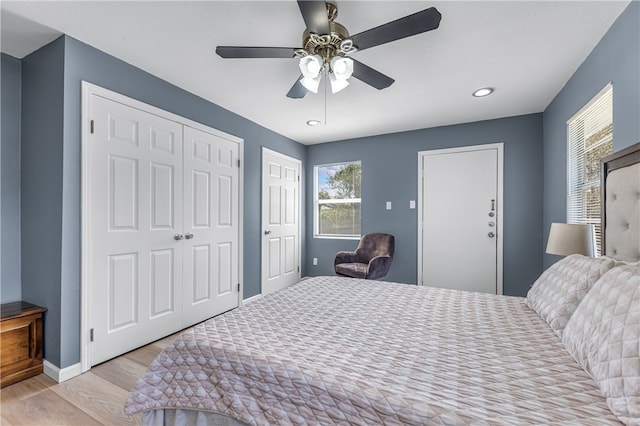 bedroom featuring multiple closets, ceiling fan, and light hardwood / wood-style flooring