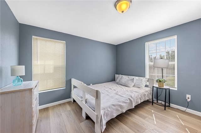 bedroom with multiple windows and light hardwood / wood-style flooring