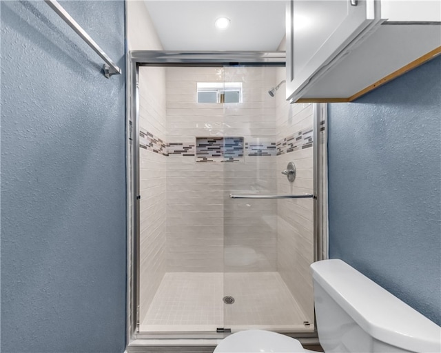 bathroom featuring walk in shower and toilet