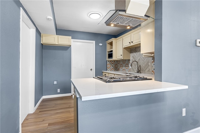 kitchen with island exhaust hood, sink, cream cabinetry, and stainless steel gas stovetop