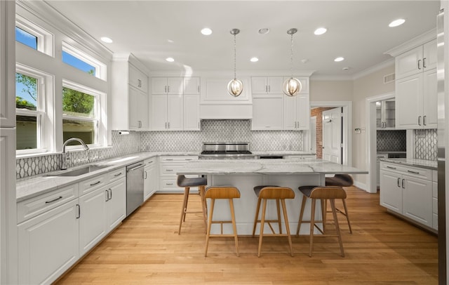 kitchen with a kitchen island, white cabinetry, sink, and light wood-type flooring