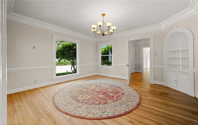 spare room featuring hardwood / wood-style flooring, an inviting chandelier, and ornamental molding