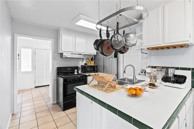 5830 Woodhaven Dr, Corpus Christi, TX 78412 - kitchen featuring tile countertops, black appliances, under cabinet range hood, white cabinetry, and light tile patterned flooring