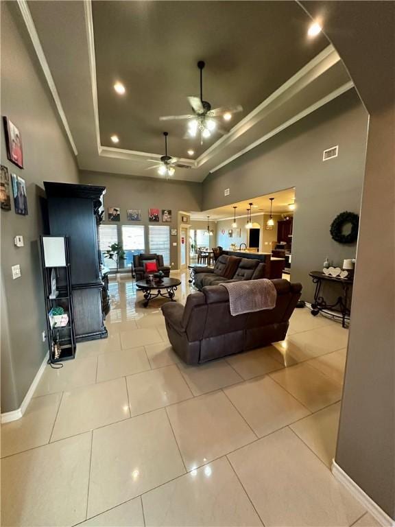 tiled living room featuring a raised ceiling and ceiling fan