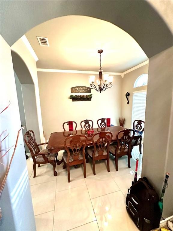 dining room with crown molding, light tile patterned flooring, and a notable chandelier