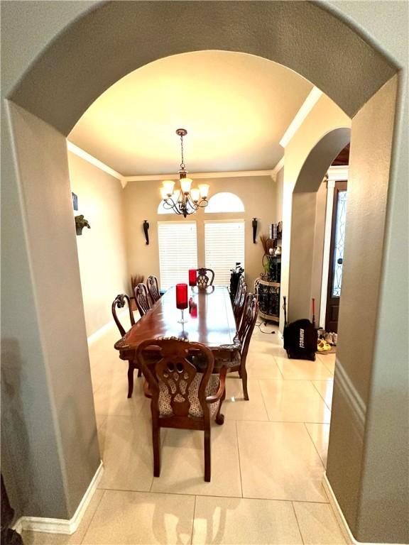 dining room with an inviting chandelier, ornamental molding, and light tile patterned floors