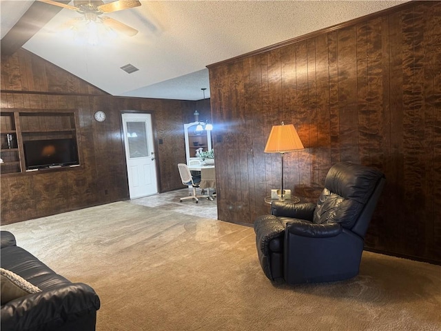 carpeted living area with lofted ceiling, visible vents, wood walls, and ceiling fan