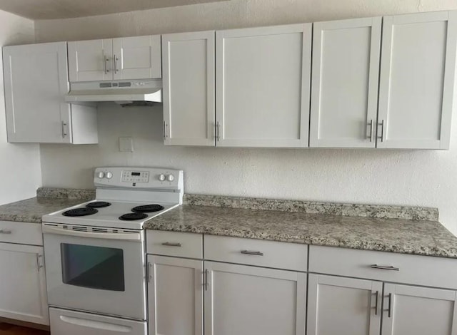 kitchen featuring light stone countertops, white cabinets, and electric range