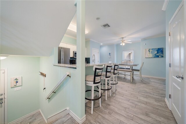 staircase featuring ornamental molding, hardwood / wood-style flooring, ceiling fan, and sink