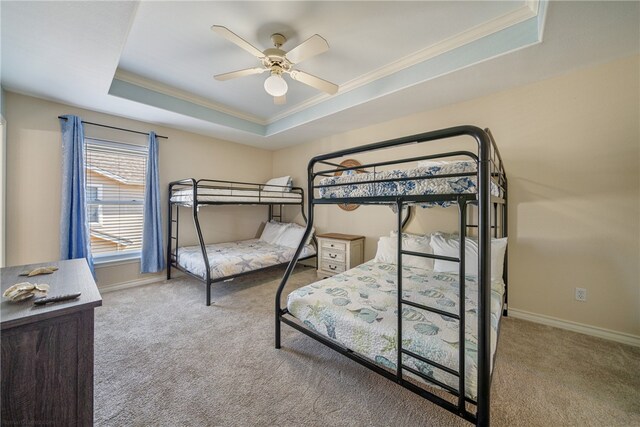 bedroom featuring light colored carpet, ceiling fan, crown molding, and a tray ceiling