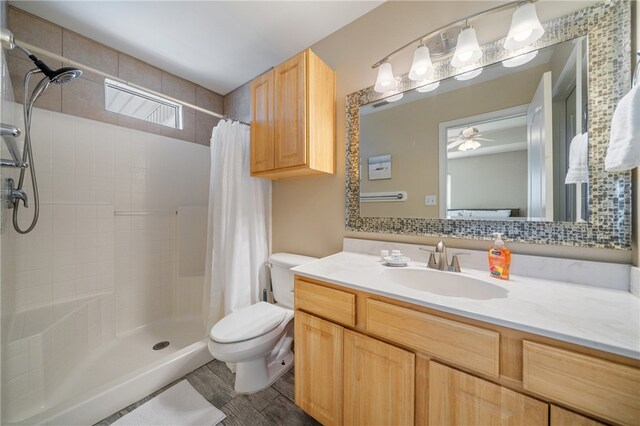 bathroom with toilet, decorative backsplash, vanity, ceiling fan, and walk in shower