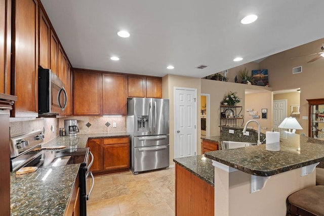 kitchen with sink, a breakfast bar area, dark stone counters, a kitchen island, and stainless steel appliances