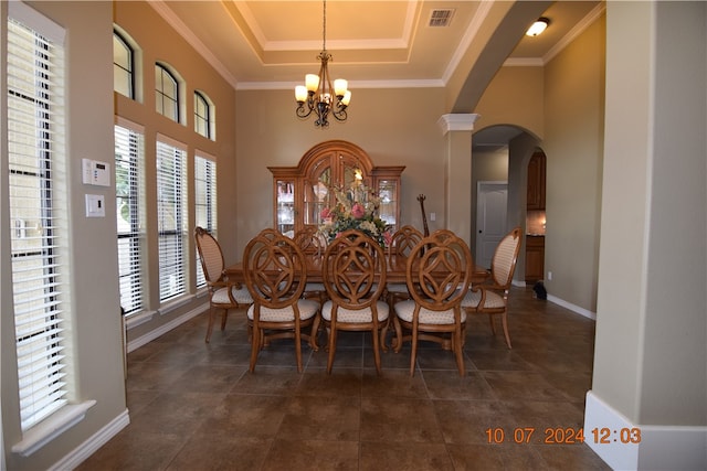 dining room featuring ornate columns, crown molding, a raised ceiling, and an inviting chandelier