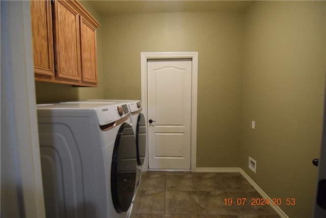 laundry room featuring cabinets, dark tile patterned floors, and washer and clothes dryer