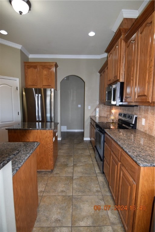 kitchen with stainless steel appliances, dark stone countertops, decorative backsplash, and a center island