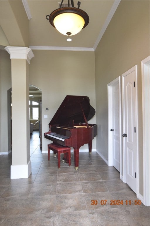 miscellaneous room with a towering ceiling, crown molding, and decorative columns