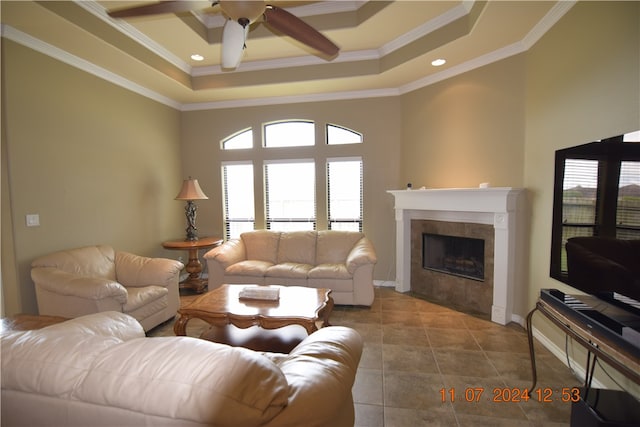 living room featuring tile patterned floors, crown molding, a tiled fireplace, a high ceiling, and ceiling fan