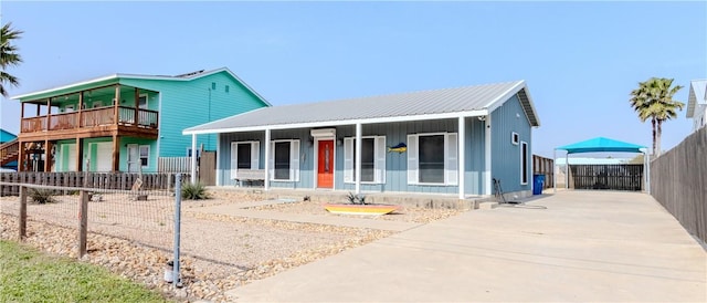 view of front of home featuring driveway, covered porch, fence, and metal roof