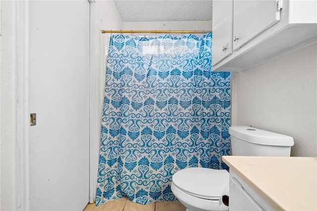 bathroom featuring vanity, toilet, tile patterned flooring, and a textured ceiling