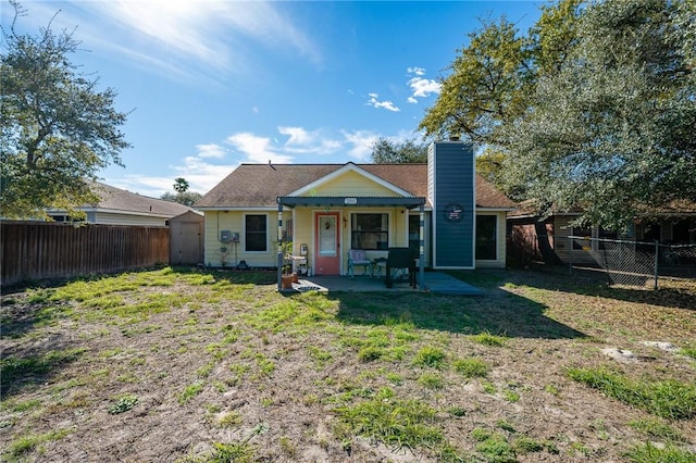 back of property with a patio, a yard, and a shed