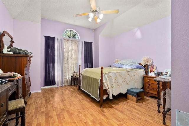 bedroom with ceiling fan, light hardwood / wood-style floors, and a textured ceiling