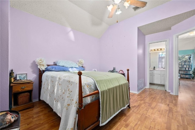 bedroom with connected bathroom, lofted ceiling, light wood-type flooring, ceiling fan, and a textured ceiling