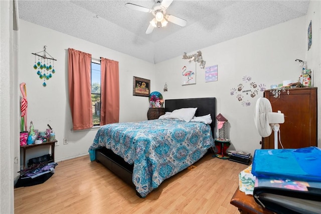 bedroom with ceiling fan, wood-type flooring, and a textured ceiling