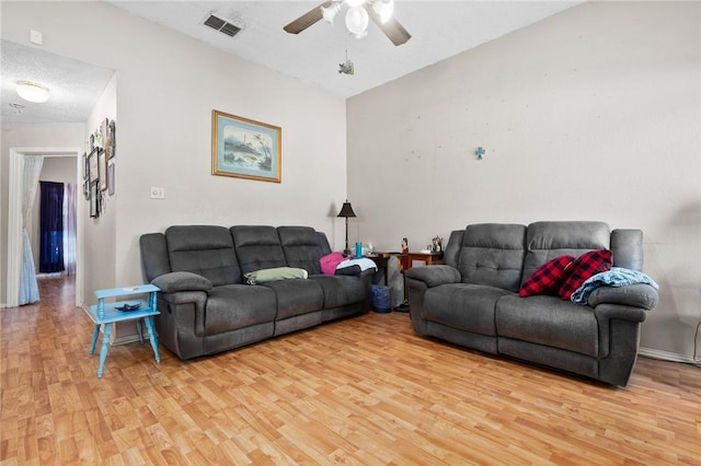 living room featuring ceiling fan, a textured ceiling, and light hardwood / wood-style floors