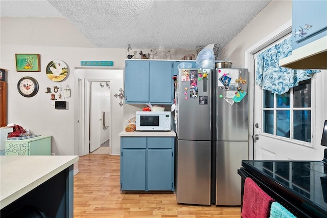 kitchen with blue cabinets, light wood-type flooring, stainless steel fridge, black range with electric stovetop, and a textured ceiling