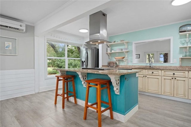 kitchen with a center island, a wall mounted air conditioner, stainless steel fridge, island range hood, and a breakfast bar