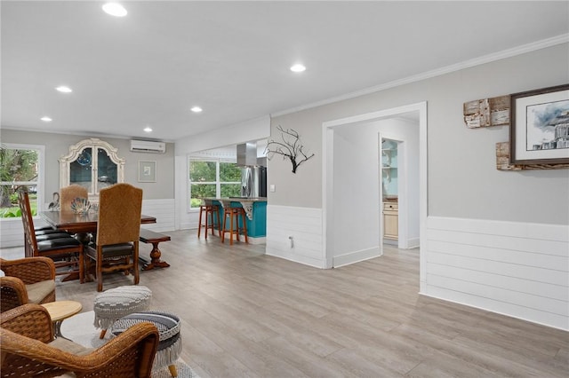 dining room featuring light hardwood / wood-style floors, crown molding, and a wall mounted AC