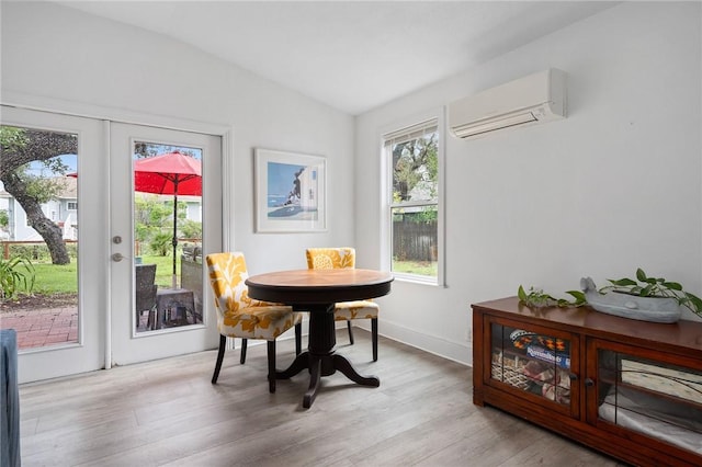 dining space featuring an AC wall unit, french doors, lofted ceiling, and light wood-type flooring