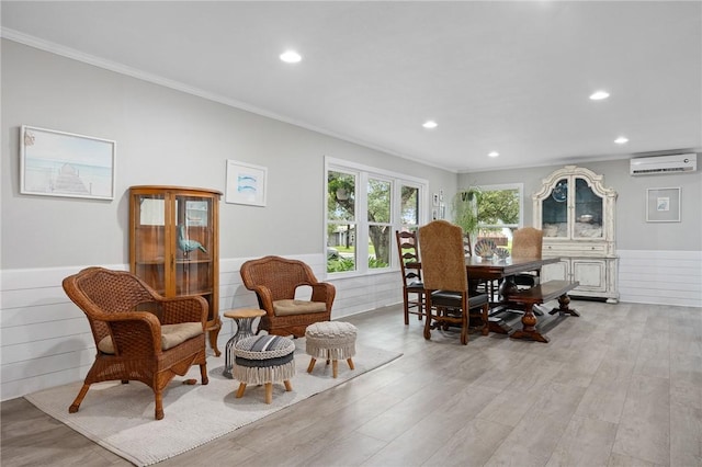 sitting room featuring a wall mounted AC, light hardwood / wood-style flooring, and ornamental molding