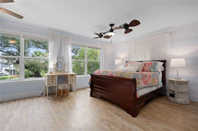 bedroom with multiple windows, light hardwood / wood-style flooring, and ceiling fan