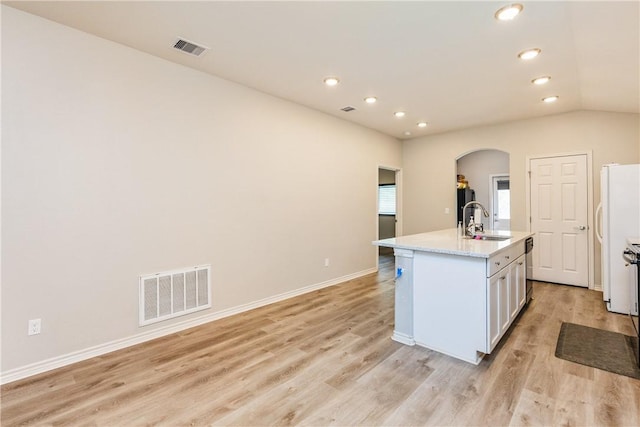 1517 Dorado St, Corpus Christi, TX 78417 - kitchen with arched walkways, light wood finished floors, white cabinetry, recessed lighting, and a center island with sink