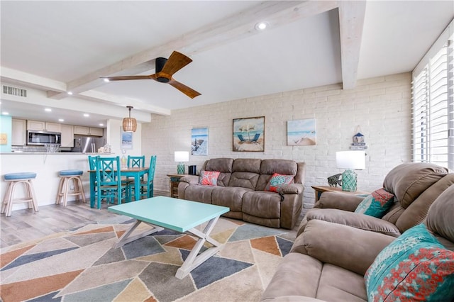 living room featuring ceiling fan, brick wall, beam ceiling, and light hardwood / wood-style flooring