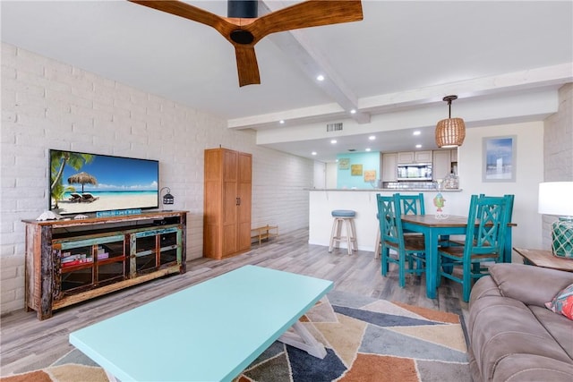 living room featuring beam ceiling, light hardwood / wood-style flooring, and brick wall