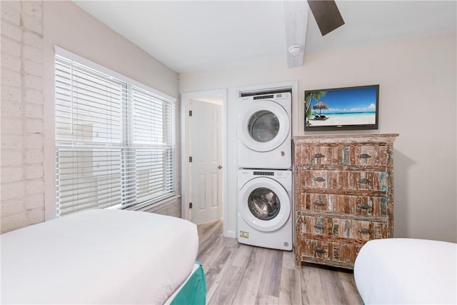 laundry area with stacked washer / drying machine and light hardwood / wood-style flooring