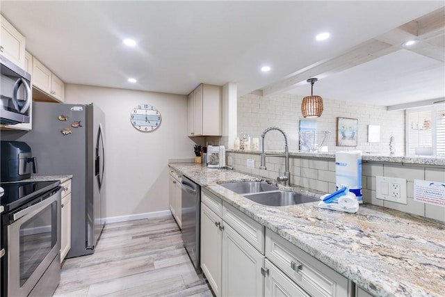 kitchen featuring tasteful backsplash, white cabinetry, sink, hanging light fixtures, and stainless steel appliances