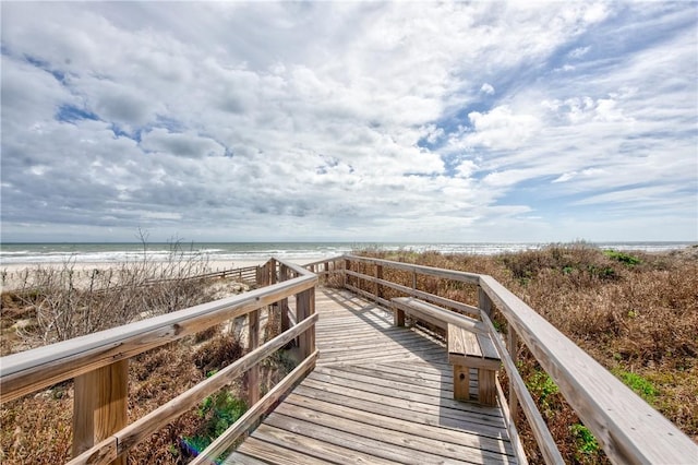 view of property's community with a water view and a beach view