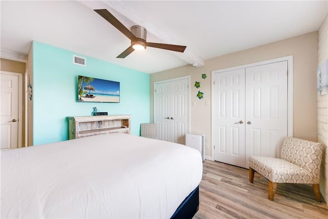 bedroom featuring multiple closets, ceiling fan, and light hardwood / wood-style flooring